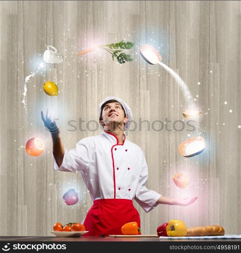 Cook at kitchen. Young man at kitchen juggling with ingredients