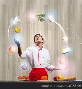 Cook at kitchen. Young man at kitchen juggling with ingredients