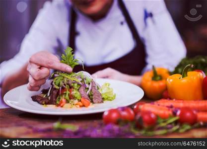 cook chef decorating garnishing prepared meal dish on the plate in restaurant commercial kitchen. cook chef decorating garnishing prepared meal