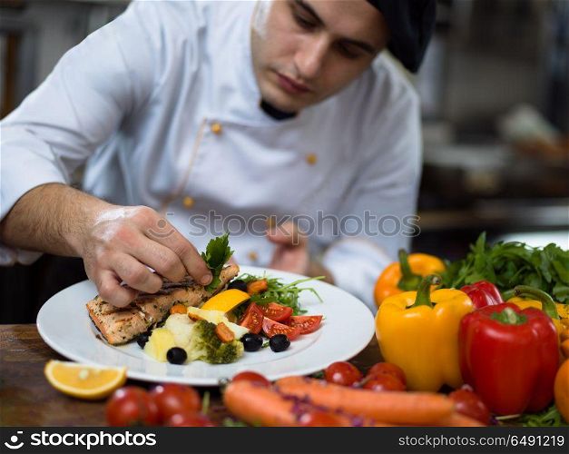 cook chef decorating garnishing prepared meal dish on the plate in restaurant commercial kitchen. cook chef decorating garnishing prepared meal