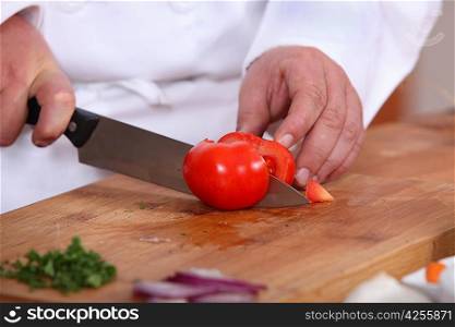 Cook cutting a tomato