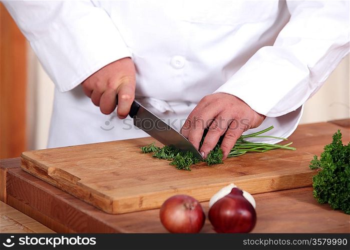 Cook cutting parsley on a chopping board