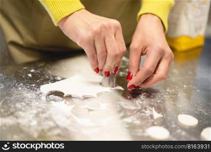 cook in the kitchen carves a circle of dough for cookies