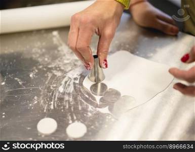 cook in the kitchen carves a circle of dough for cookies