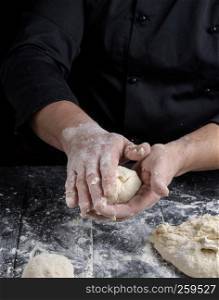 cook making dough balls on a black wooden table, close up