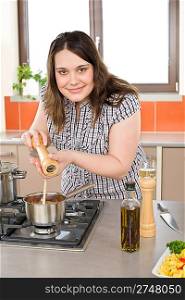 Cook - plus size happy woman with Italian food and spice in modern kitchen