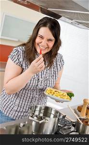 Cook - plus size smiling woman with chili pepper and tortellini cooking Italian cousine in modern kitchen
