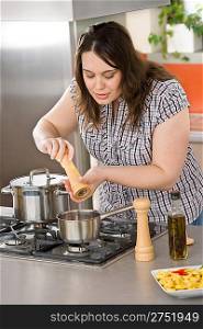 Cook - plus size woman preparing Italian food in modern kitchen with stove, pot and pan
