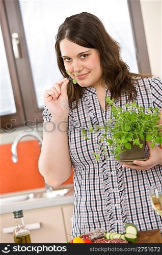 Cook - plus size woman with herb and vegetable in modern kitchen