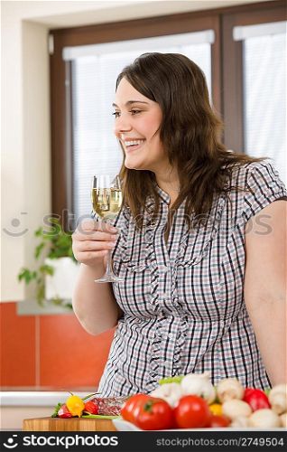 Cook - plus size woman with white wine and vegetable in modern kitchen
