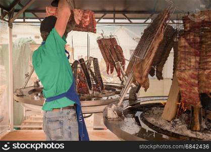 Cook prepares the meat to roast on the grill. Argentine asado.