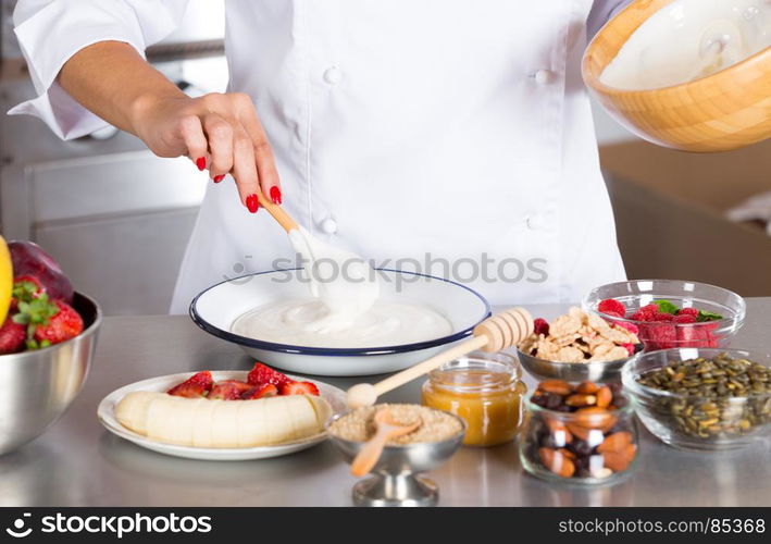 Cook preparing a dessert made with yogurt fruits and cereals