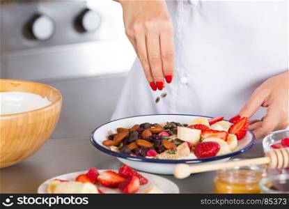 Cook preparing a dessert made with yogurt fruits and cereals