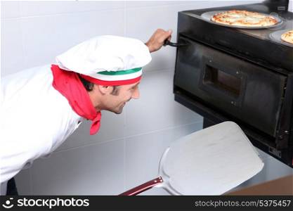 Cook watching pizzas in oven