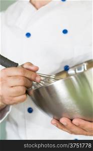 Cook whisking cream in the kitchen to make a cake