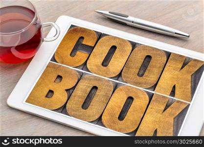 cookbook word abstract - text in vintage letterpress wood type on a digital tablet with a cup of tea