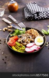 Cooked Buckwheat with avocado and mushrooms served in a bawl for breakfast. Gluten free meal.