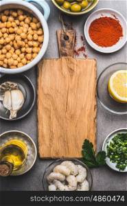 Cooked Chickpeas and various Healthy ingredients for salad around wooden cutting board, top view
