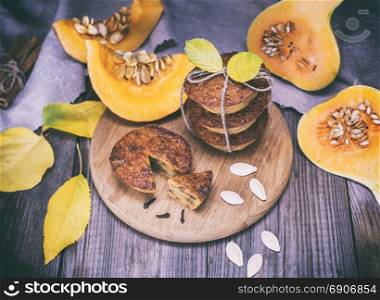 cooked cupcakes of pumpkin on a wooden board, next to fresh pieces of pumpkin