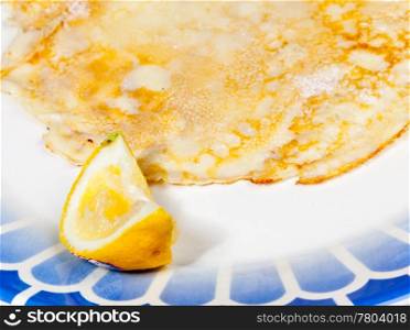 Cooked homemade pancake and lemon on blue plate
