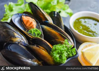 Cooked Mussels with herbs lemon and dark plate background / Fresh seafood shellfish on bowl and spicy sauce in the restaurant mussel shell food