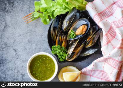 Cooked Mussels with herbs lemon and dark plate background / Fresh seafood shellfish on bowl and spicy sauce salad in the restaurant mussel shell food