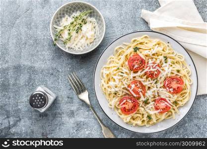 cooked noodles on a table in a plate with tomatoes, parmesan cheese and spices