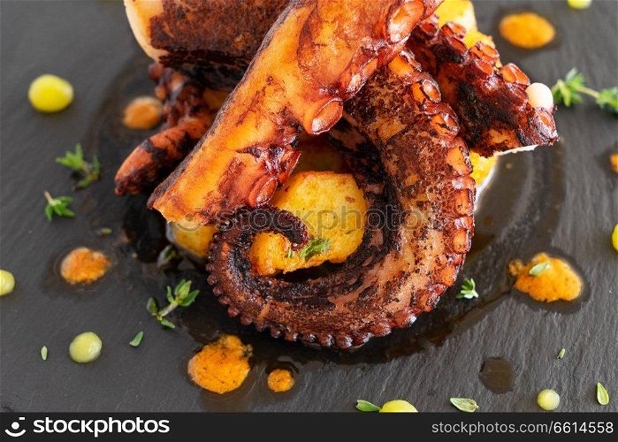 Cooked octopus dish served on black plate. Cooked octopus dish