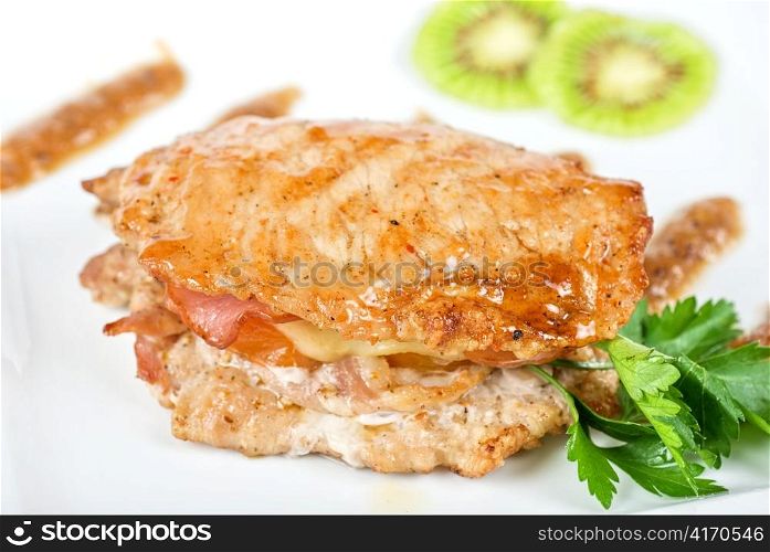 Cooked pork chop on a white plate with kiwi and parsley