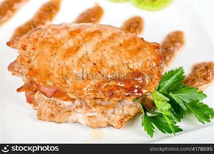 Cooked pork chop with kiwi and parsley on a white