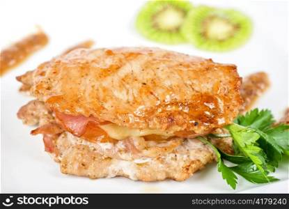 Cooked pork chop with kiwi and parsley on a white