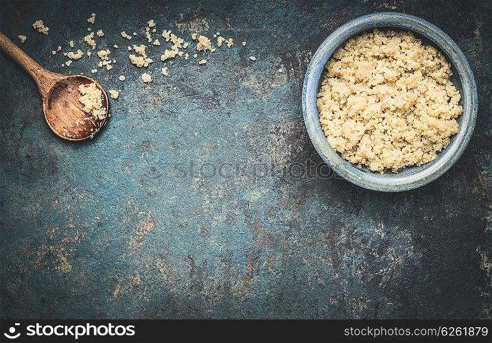 Cooked quinoa in blue bowl with cooking wooden spoon on dark rustic background, top view, place for text: recipes and menus, horizontal. Vegan Superfood, healthy eating and nutrition or diet concept.