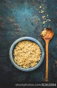 Cooked quinoa in bowl with cooking wooden spoon on dark rustic background, top view, place for text: recipes and menus, vertical. Vegan Superfood, healthy eating and nutrition or diet concept.