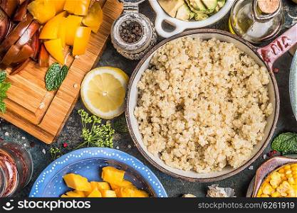 Cooked quinoa in pot with fresh fruits and vegetables ingredients for tasty cooking , preparation on rustic kitchen table, top view, close up