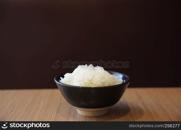 Cooked rice in bowl isolated in wood background