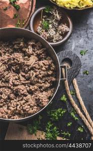 Cooked savory ground or minced meat on dark rustic kitchen table
