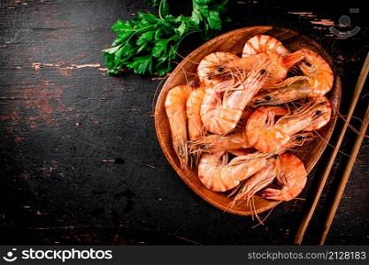 Cooked shrimp in a plate with parsley. On a rustic dark background. High quality photo. Cooked shrimp in a plate with parsley.