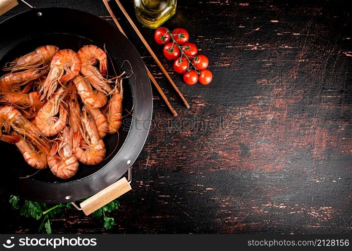 Cooked shrimp in a saucepan with parsley and tomatoes. On rustic dark background. High quality photo. Cooked shrimp in a saucepan with parsley and tomatoes.