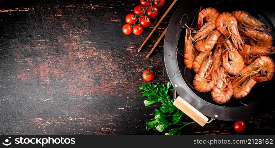 Cooked shrimp in a saucepan with parsley and tomatoes. On rustic dark background. High quality photo. Cooked shrimp in a saucepan with parsley and tomatoes.