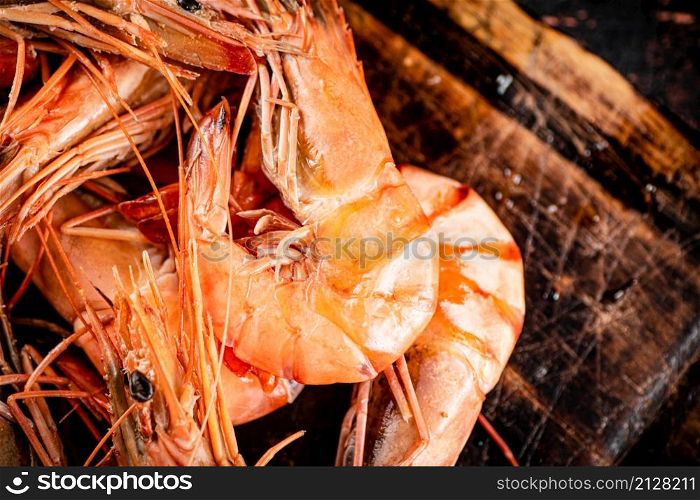 Cooked shrimp on a wooden cutting board. Against a dark background. High quality photo. Cooked shrimp on a wooden cutting board.