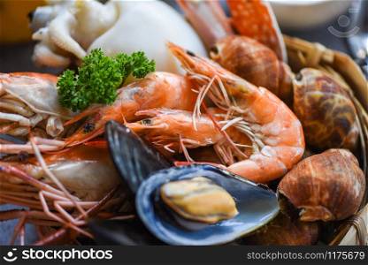 Cooked steamer food served seafood buffet concept / Fresh shrimps prawns squid mussels spotted babylon shellfish crab and seafood sauce lemon on plate background