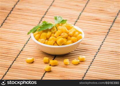 cooked sweet corn seeds in a bowl on a wooden table. canned corn