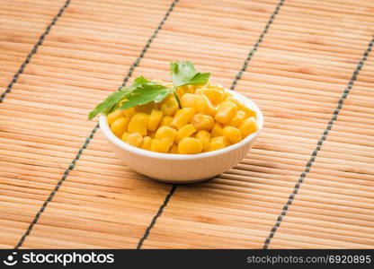 cooked sweet corn seeds in a bowl on a wooden table. canned corn