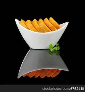 Cooked sweet potato slices (lat. Ipomoea batatas) in white bowl garnished with a parsley leaf and photographed on black (Selective Focus, Focus on the front) . Cooked Sweet Potato with Parsley on Black