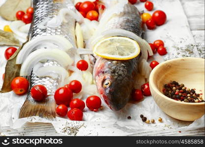 Cooked to cooking fish. Two carcasses of raw marine fish in seasonings and tomatoes