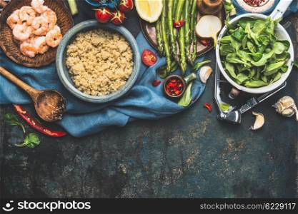Cooked white quinoa in bowl with fresh vegetables cooking ingredients on dark rustic background, top view, border. Superfood , healthy eating or vegetarian food concept.