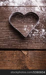 Cookie cutter heart shape on the kitchen table and flour
