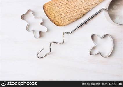 cookie cutters and wooden spoon on white wooden background