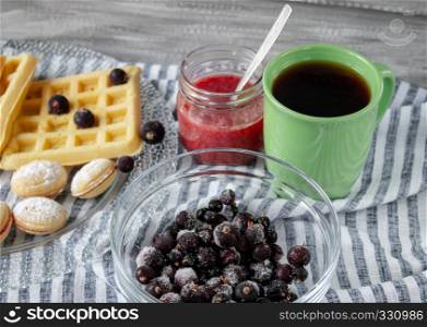 Cookies and berries on a bowl, tea in a green cup, close-up.. Cookies and berries on a bowl, tea in a green cup.