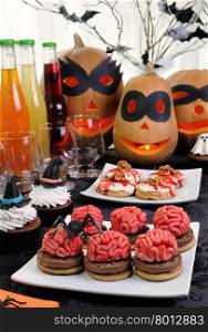 Cookies brains of marzipan on a table with a variety of sweets in honor of Halloween